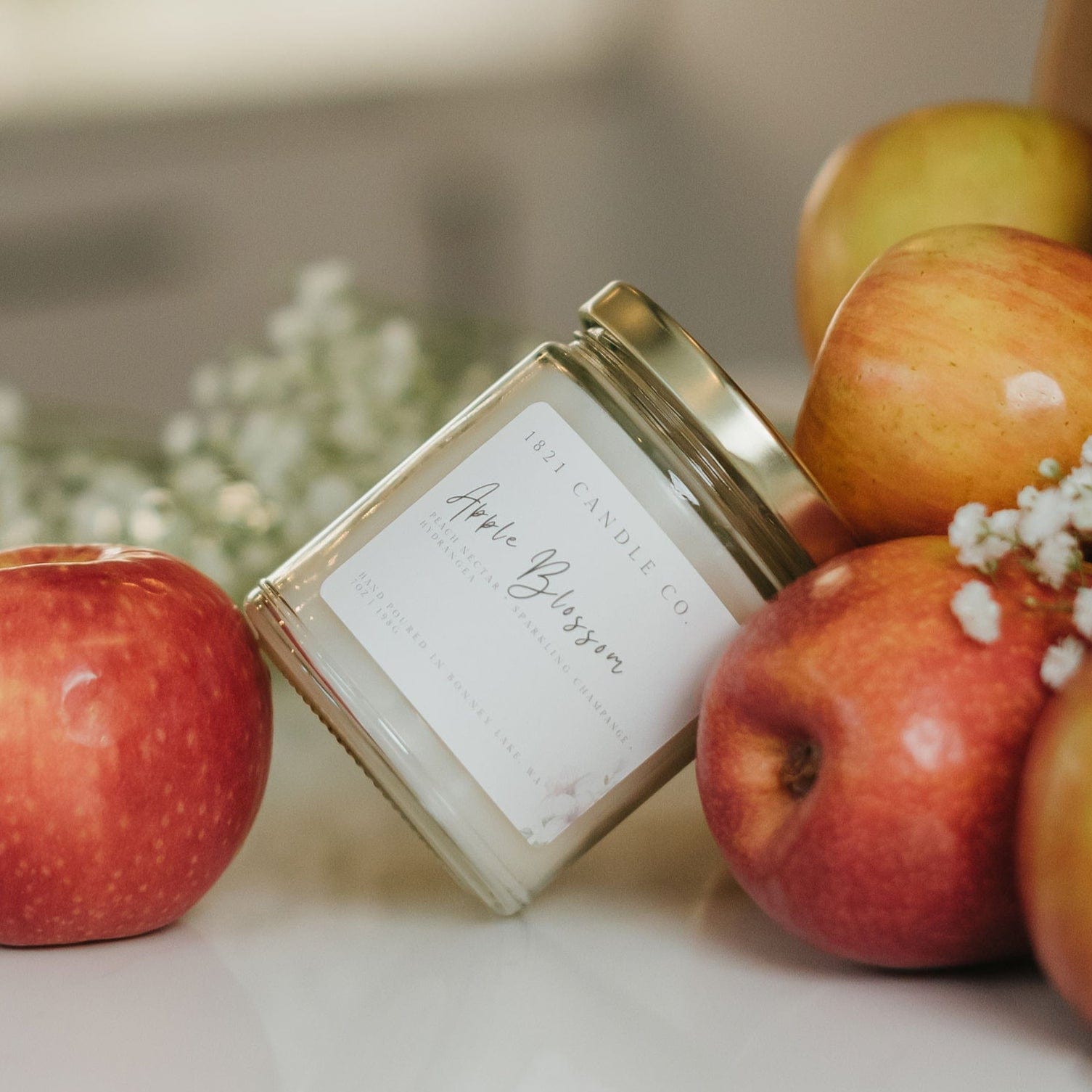 Apple Blossom jar candle nestled in farm fresh apples, phthalate free handmade candle inspired by springtime blooms.