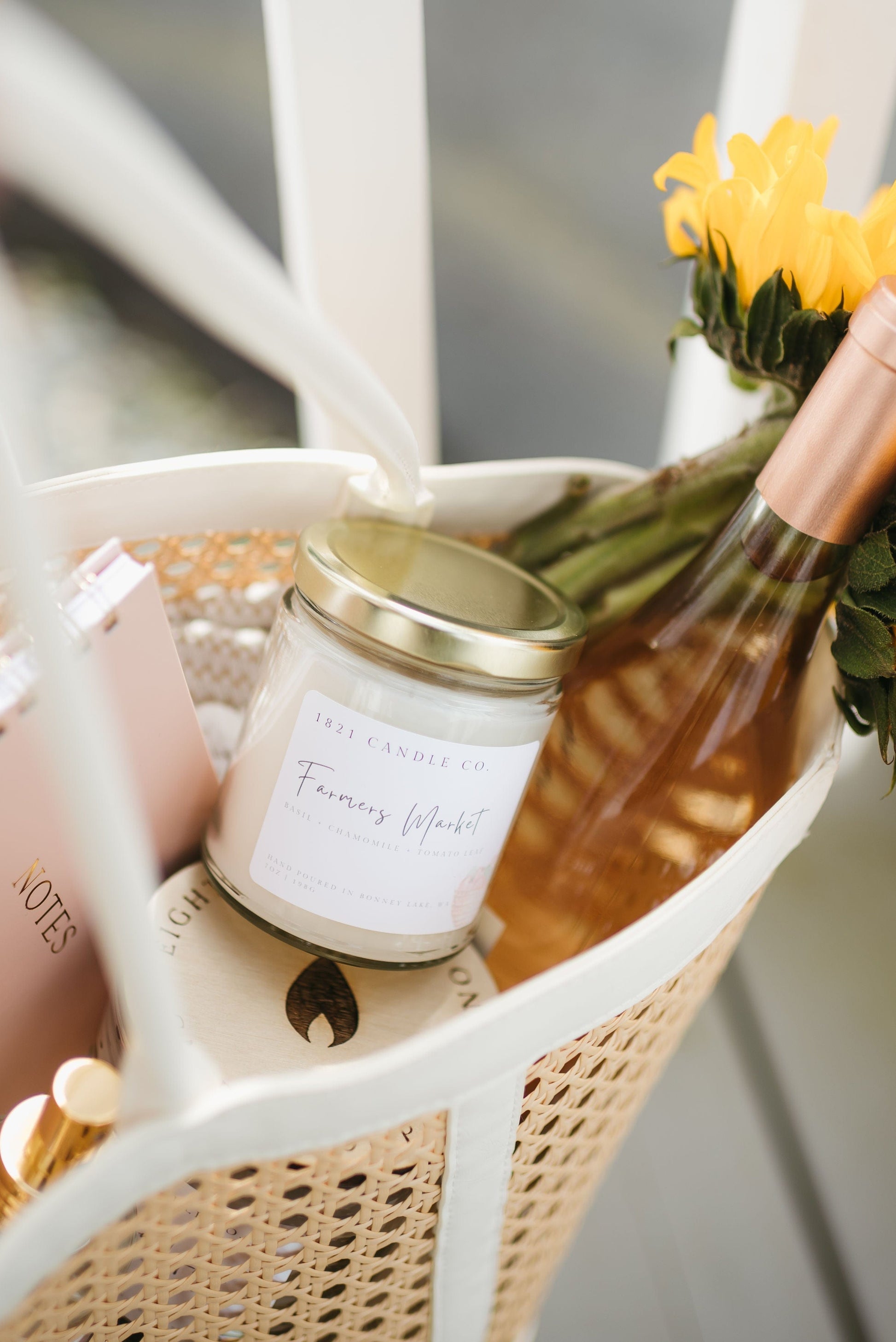 Farmers Market summer candle handmade in Bonney Lake by 1821 Candle co in a market basket with summer essentials including a notebook and sunflowers.