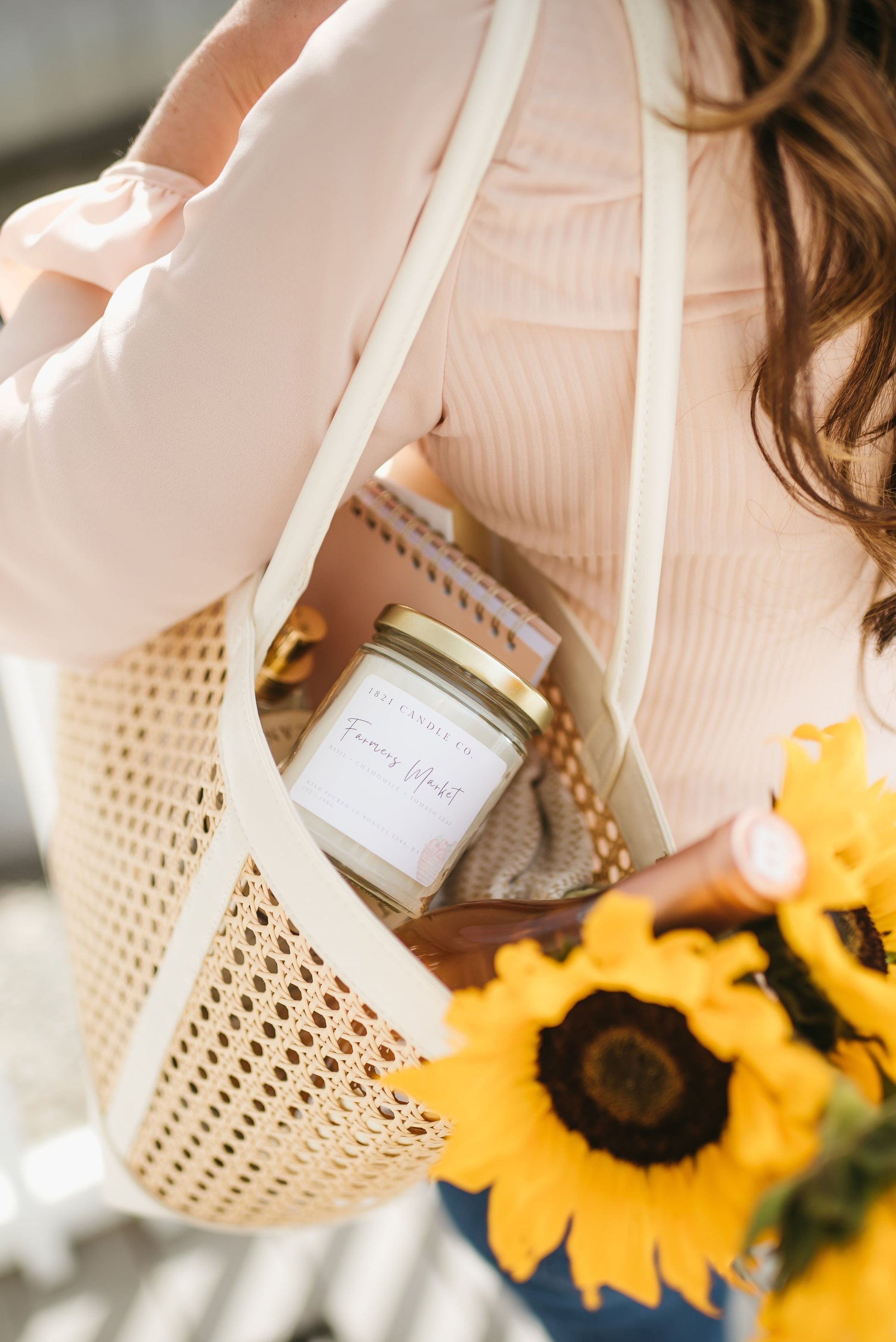 Farmers Market summer candle by 1821 Candle Co tucked into a market basket with summer essentials, including a notebook and sunflowers.
