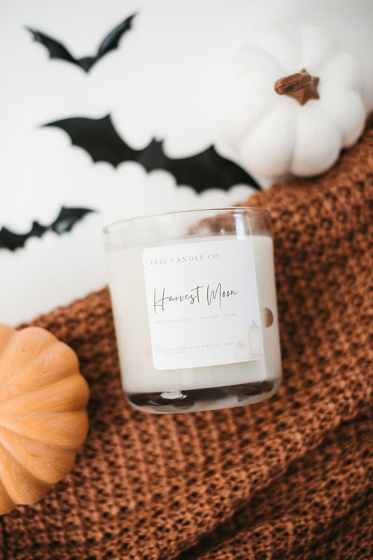 Soy Blend Candle named Harvest Moon with Halloween decorations including pumpkins and bats.