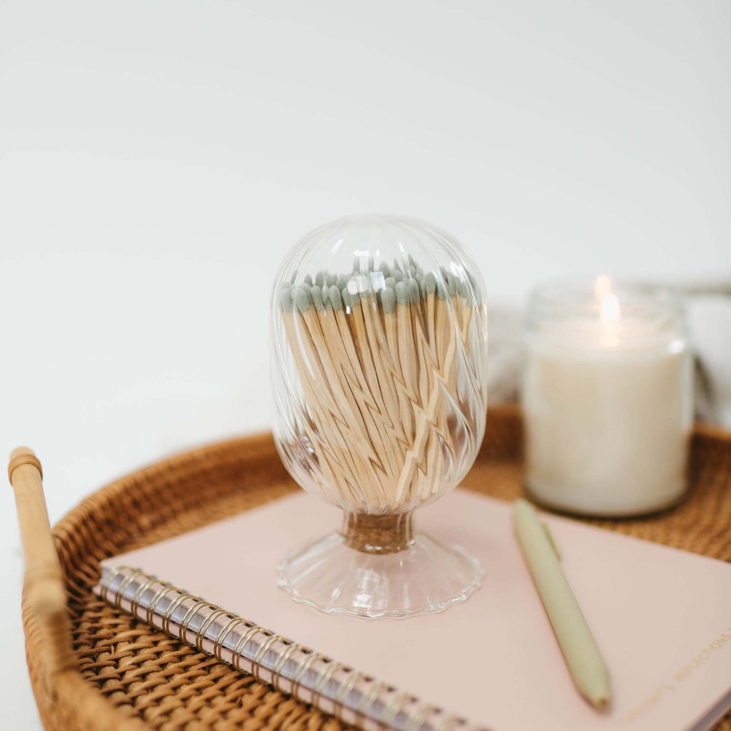 glass match cloche filled with safety matches styled on a woven tray with a notebook, a pen and lit candle - an elegant giftable accessory by 1821 Candle Co.