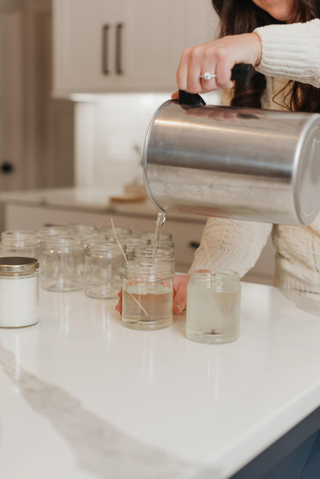 Pouring handmade non toxic clean burning coconut apricot wax candles in a kitchen setting.