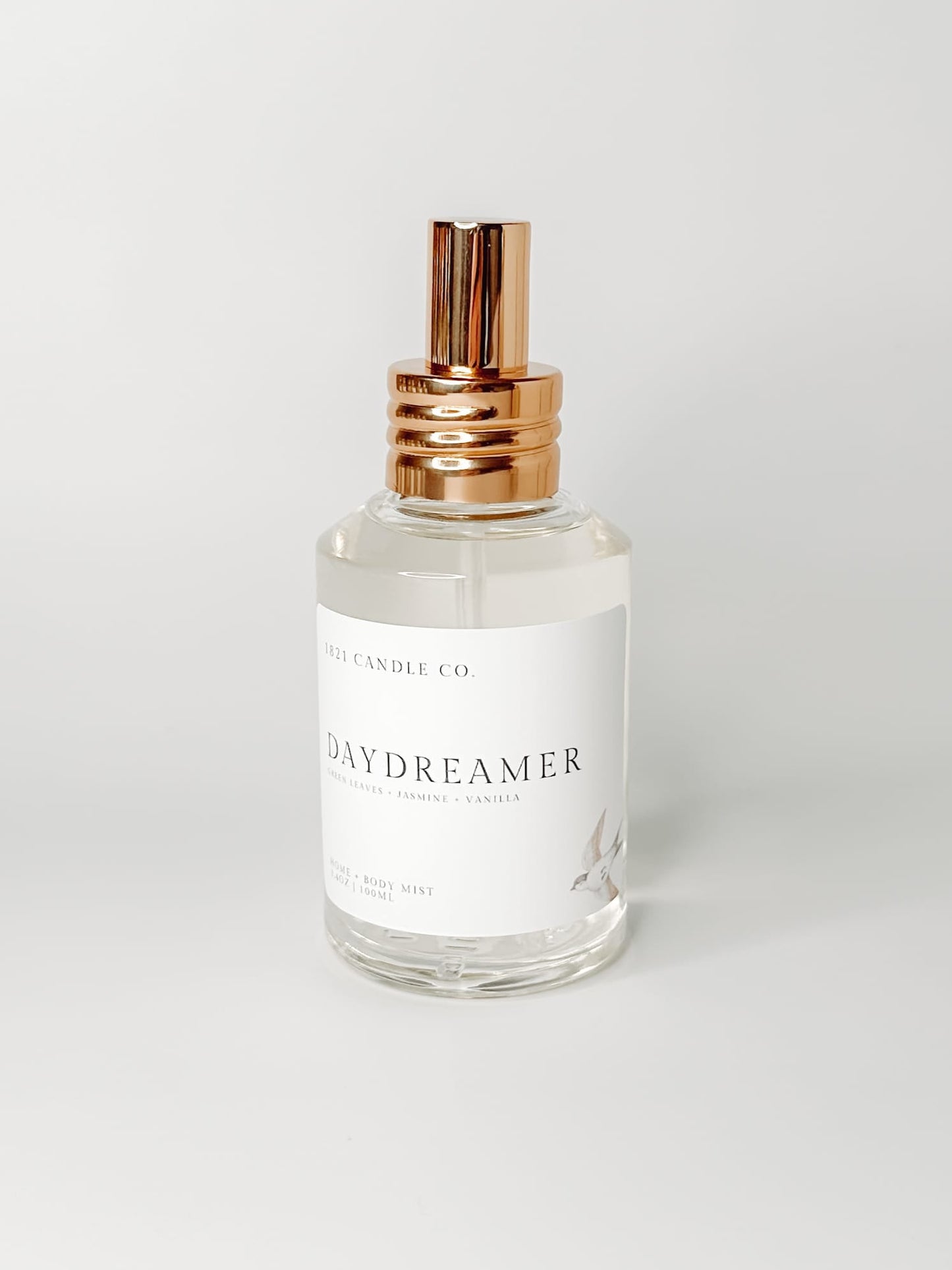Daydreamer Home and Body Mist with notes of sandalwood, creamy vanilla and soft jasmine in a clear glass bottle and gold spray cap on a white background.