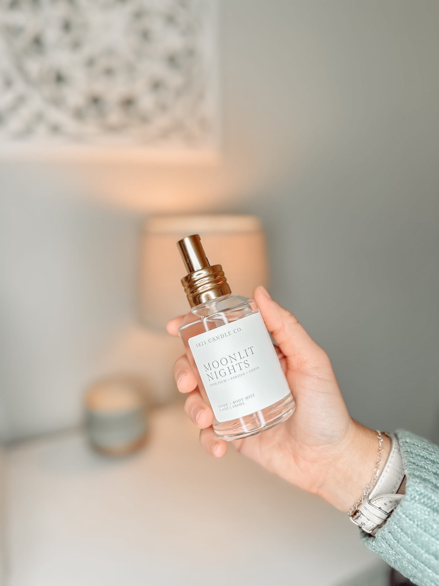 Moonlit Nights Home + Body Mist held in a hand with a background of a dresser. Made in small batches in Washington by 1821 Candle Co.