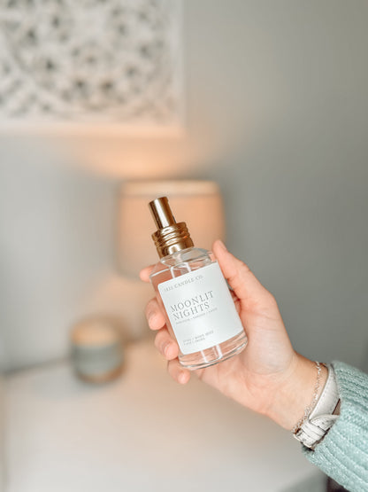 Moonlit Nights Home + Body Mist held in a hand with a background of a dresser. Made in small batches in Washington by 1821 Candle Co.