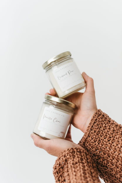 Orchard Pear and Vanilla Chai Fall Candles held in someone's hands against a white background.