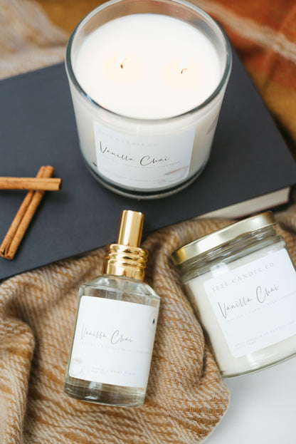 Vanilla Chai Fall Candles and home air freshener, body spray laying on a warm cozy fall sweater
