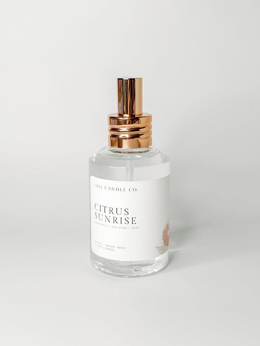 Citrus Sunrise non toxic, clean home and body spray in a clear spray bottle with a gold lid on a white background. Made in small batches in Washington