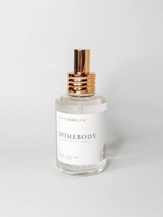 homebody body mist, room spray, home air freshener by 1821 candle co. A clear glass bottle with a gold top with notes of vanilla, cashmere, marshmallow by 1821 candle co. Made in small batches in washington.