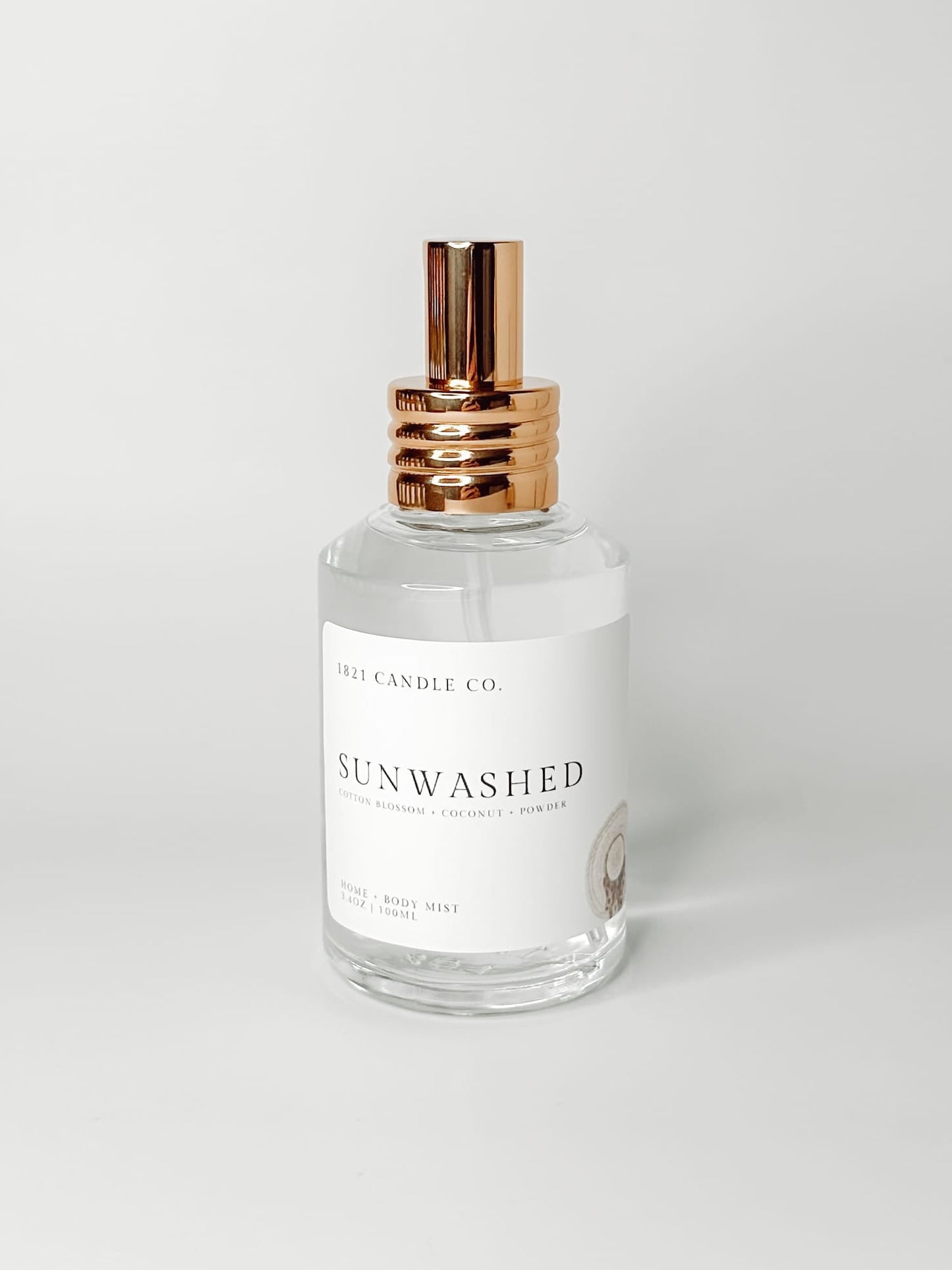Sunwashed clean, phthalate free home and body mist made by 1821 candle go in washington in a clear glass bottle with a gold spray cap on a white background. Notes of coconut, powder and cotton blossom.