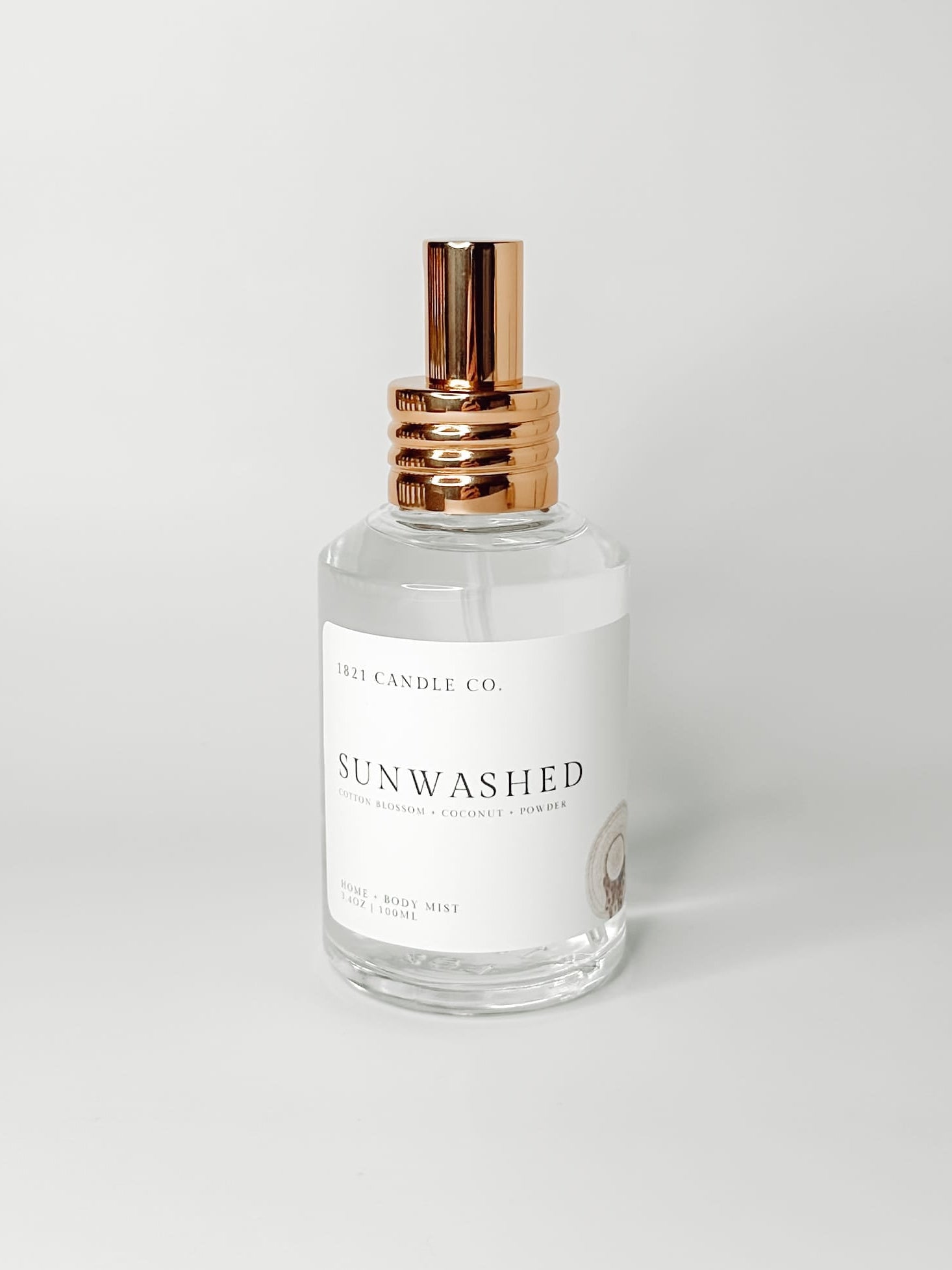 Sunwashed clean, phthalate free home and body mist made by 1821 candle go in washington in a clear glass bottle with a gold spray cap on a white background. Notes of coconut, powder and cotton blossom.